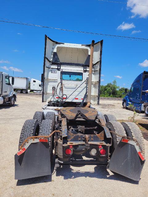 Conventional daycab tractor rear view showing fifth wheel, dual rear axles, and mud flaps.