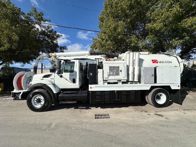 VacCon vacuum truck in serviceable condition with large hose reel and equipment compartments mounted on white truck chassis.