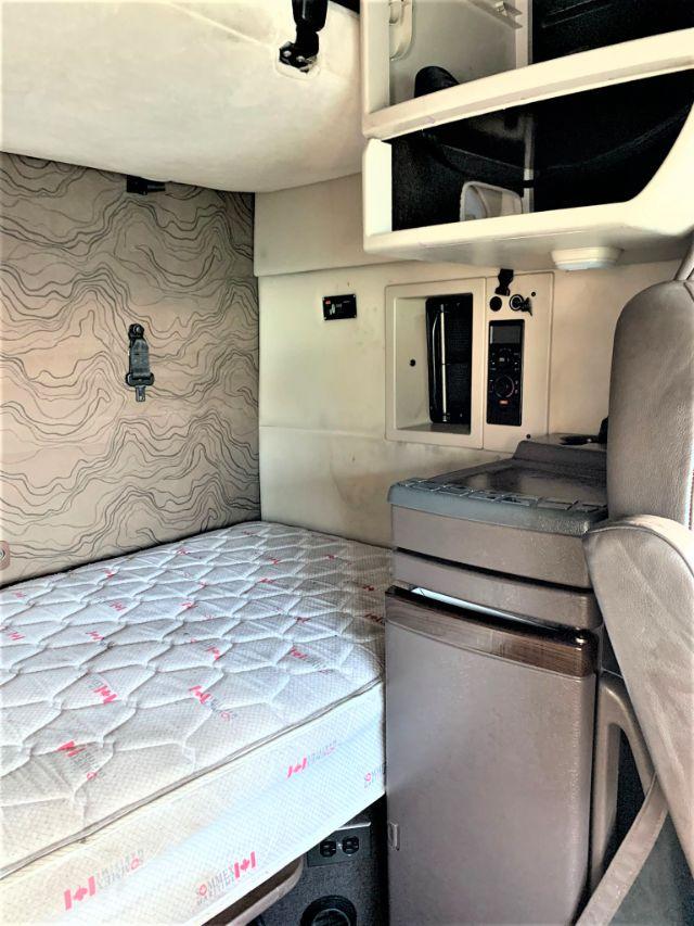 Volvo VNL 670 sleeper cab interior showing bunk bed mattress, dash area, storage cabinet, and control panel.