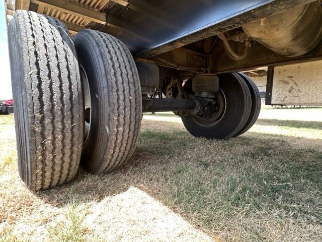 Trailer undercarriage showing dual rear axle configuration with two tires on left and one tire visible on right, undercarriage and framing of a 2019 utility flat bed trailer.