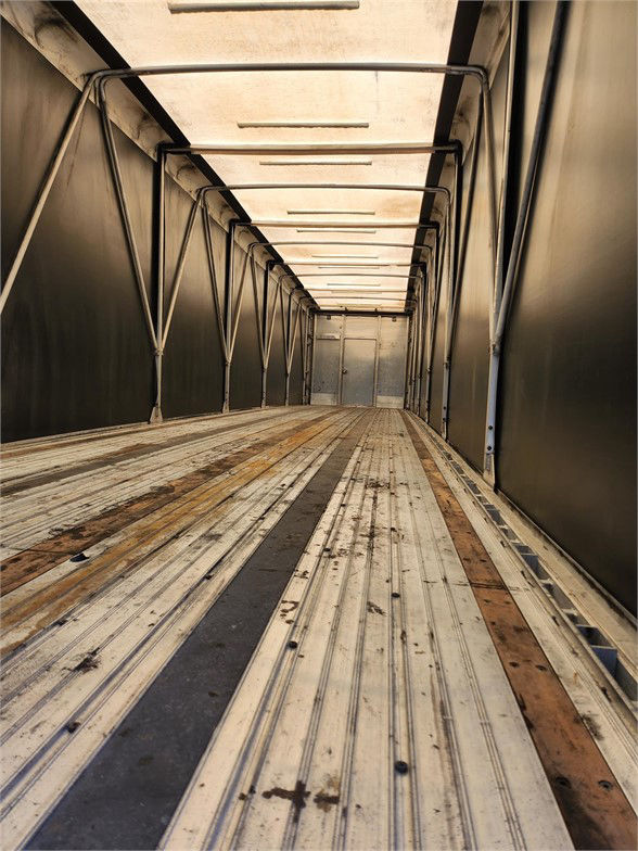 Trailer interior showing metal sidewalls and ridged wooden/metal floor with tracks, long rectangular hallway inside a Manac COMBO trailer.