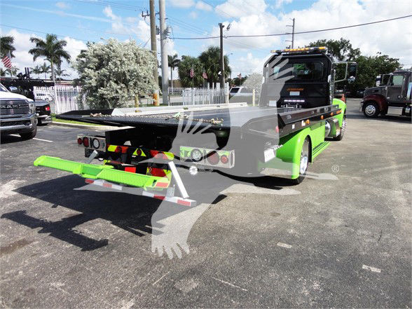 Tow truck with green and black color scheme viewed from rear-left side; ramp/bed extended; Peterbilt branding on cab; stock number J56607; license plate area visible.