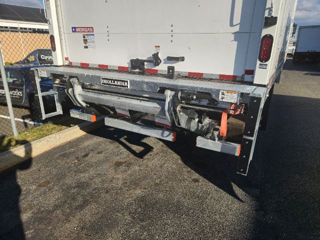 Back of a box truck showing a Dejana or similar rear underrun bar and hydraulic hoses; various stickers and taillights visible.