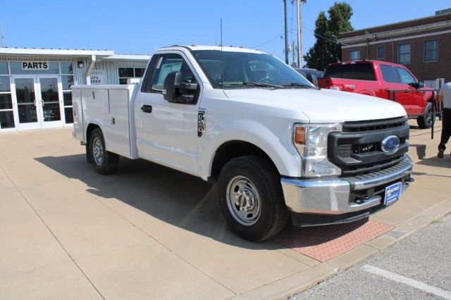Ford F-250 utility truck in white, side view showing front grille and service body with compartments.