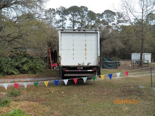 IC Corporation box truck rear view showing closed cargo door and bumper, with pennant flags in foreground and date stamp 2024/03/03.