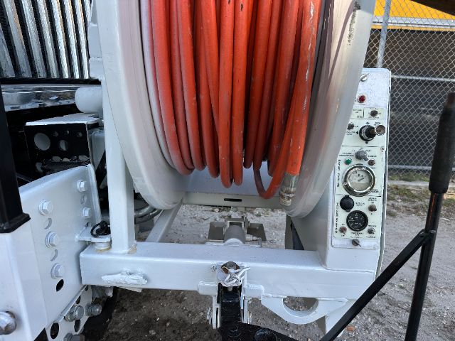 Large orange hose reel mounted on a heavy-duty truck chassis with control panel and reel housing visible on the right side.