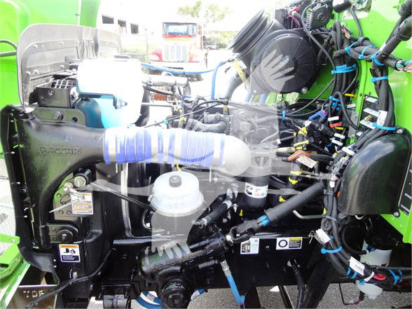 Truck engine bay of a 2022 Peterbilt 337 showing coolant reservoir, intake hoses, wiring harness, and various engine components.