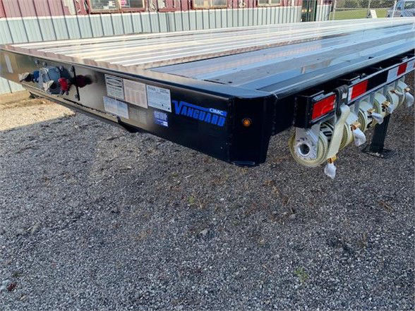 Flatbed trailer showing Vanguard branding and pulley systems at the rear, blue and black color, flat steel deck.