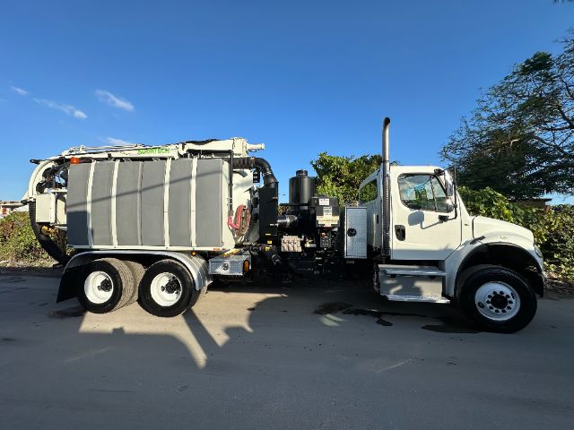 2014 Freightliner M2 vacuum truck side view showing large gray waste tank, dual rear axles, exhaust stack, and operator cab.