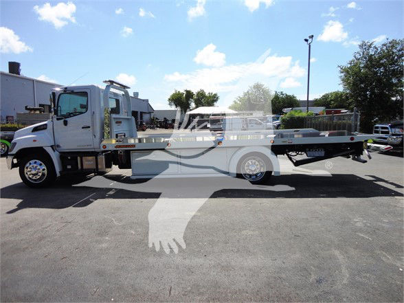 Tow truck with flatbed side view showing 2022 Hino 268A and tow bed.