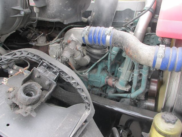 Volvo truck engine bay showing blue silicone intercooler hoses, turbocharger plumbing, belts, and surrounding engine components.
