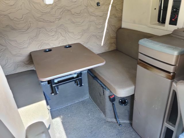 Volvo 670 sleeper cab interior with foldable table and seating area. Table surface with two cup holders, beige upholstery, and control panels visible.