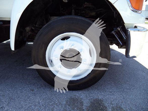 Ford F-650/FXT wheel and tire showing steel wheel and hub, front wheel well, suspension components, and part of truck body.