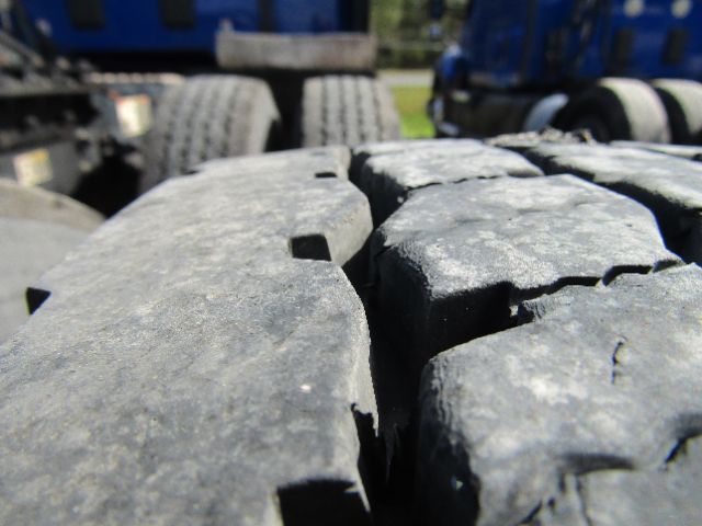 Close-up view of heavy-duty truck tires with cracked tread, part of a Kenworth T680 chassis in the background.