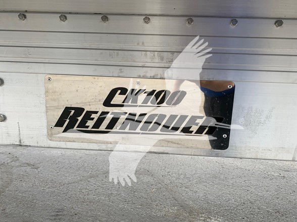 CK100 Reitnouer logo plate on flatbed trailer side door showing CK100 REITNOUER text and bird silhouette watermark.
