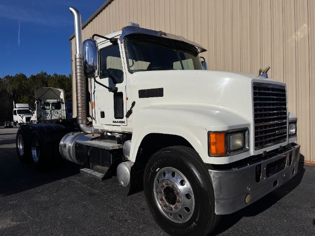 Truck bay showing 2013 Mack CHU613 Pinnacle conventional daycab with large chrome exhaust stack, white cab, front grille, and dual rear axles.