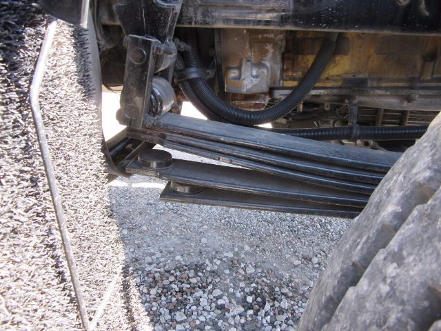 Kenworth T800 engine bay side view showing suspension leaf springs and undercarriage components.