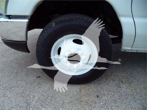 Vehicle wheel of a 2011 Ford E450 flatbed truck showing a white steel wheel and tire.