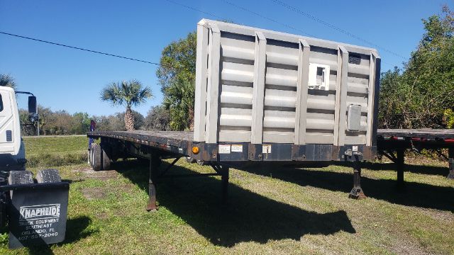 Flatbed trailer with a Large gray gooseneck end, 53x102 Great Dane. Front landing legs visible, black frame with metal storage box and ladder. Text on sign near bottom left: 'Knapheide'?