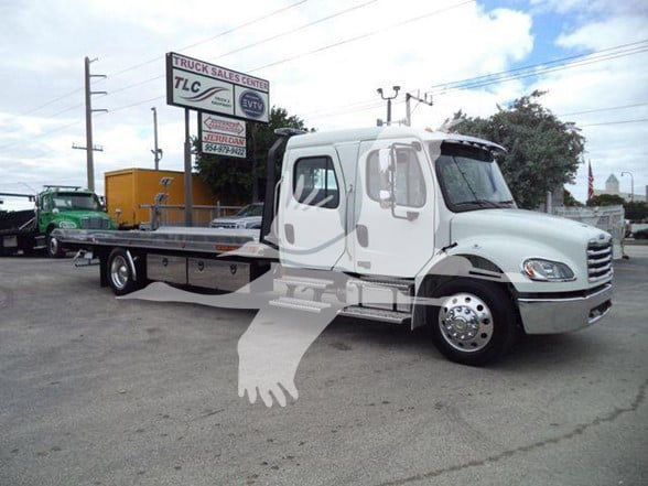 Freightliner Business Class M2 106 tow truck flatbed showing stock number JU6165FM at a dealership.