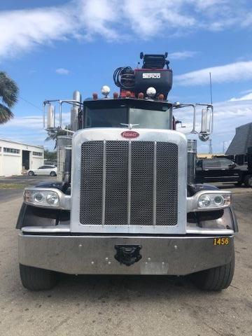 Peterbilt 388 grapple truck front view showing large grille, headlights, and bumper with black license plate area.