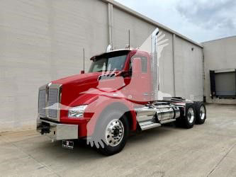 Kenworth T880 conventional day cab truck in red, front-left view showing chrome fuel tanks and steps.