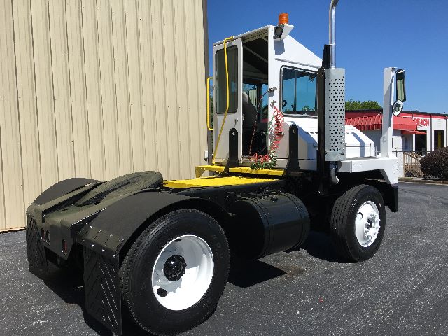Kalmar Ottawa YT30 yard truck chassis with white cab, black frame, and dual rear axles; yellow steps and safety rails.