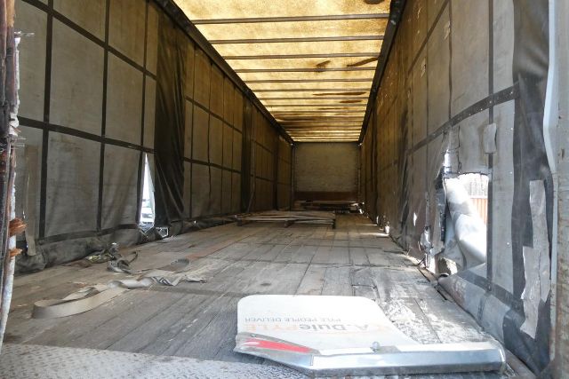 Trailer interior showing curtain side cargo area with weathered floor and side tarps.