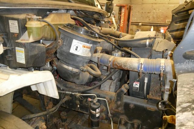 View of Freightliner M2 106 engine bay showing air intake, intercooler piping, and various hoses and reservoirs.