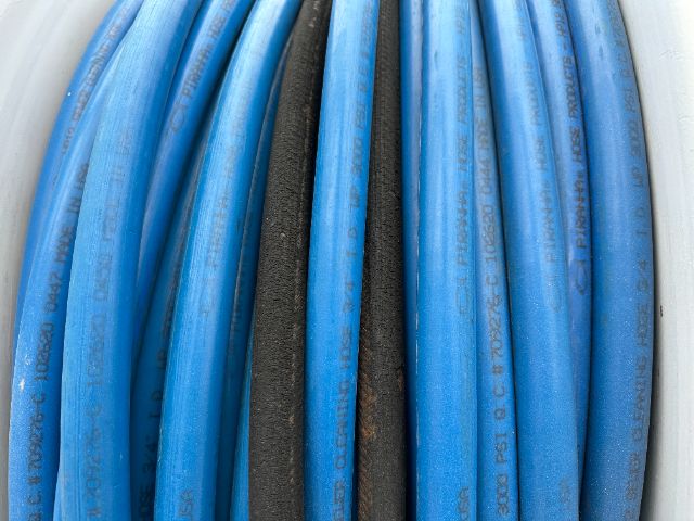 Blue hydraulic or air hoses coiled with a dark central hose, labeled with white text, in a truck component context.