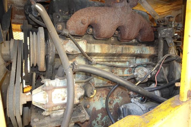 Grove RT58 crane engine bay showing exhaust manifold, belts, hoses, and pulley system.