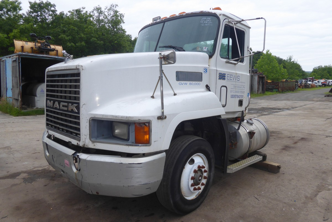 Mack CH613 convention day cab truck showing front grille with 'MACK' emblem and dual large headlights, white exterior, fuel tank on the side, and worn front bumper.