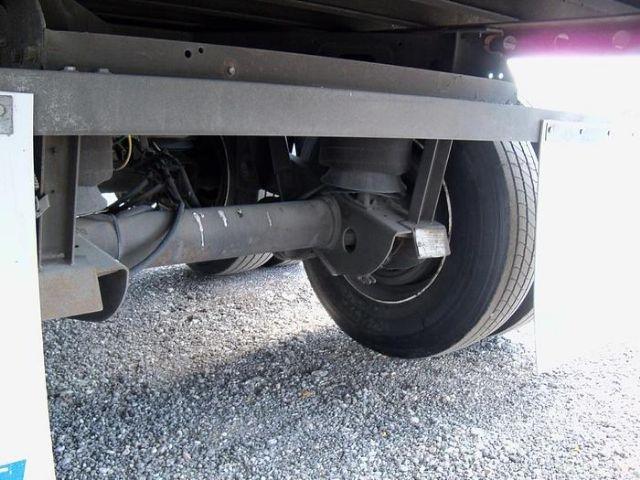 Rear undercarriage of a Vanguard dry van trailer showing suspension beam and axle with tire, undercarriage components and gravel ground.