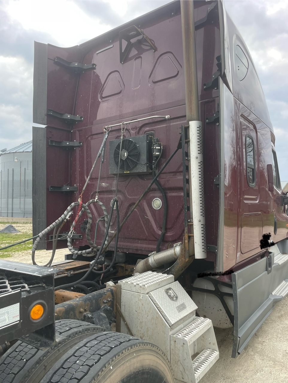 Freightliner Cascadia 125 truck cab rear with exhaust stack, heater/AC unit, and auxiliary hoses.