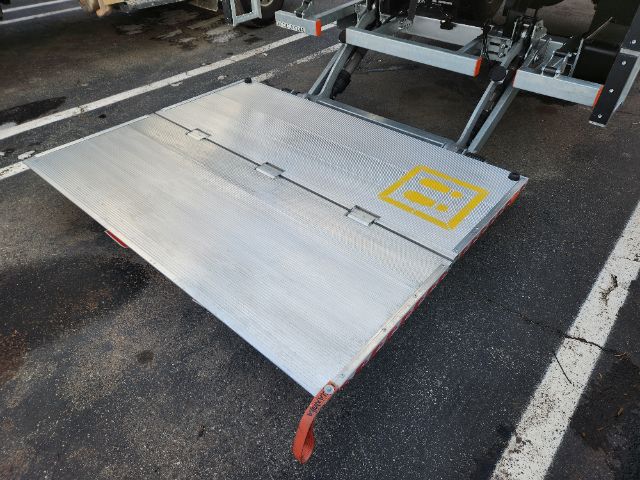 Platform/ramps attached to a Hino truck with a metal foldable loading lift at the rear. Silver aluminum surface with yellow safety graphic.