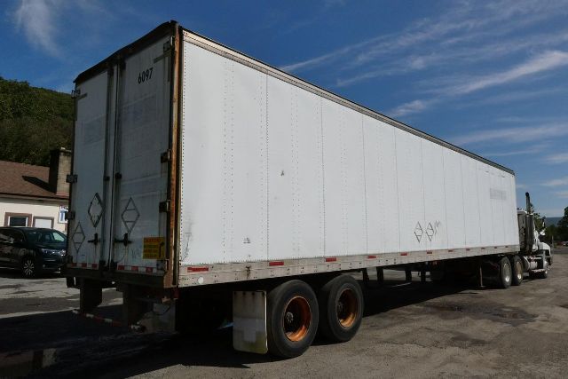Fruehauf FB9T248 trailer with white sides and dual rear doors, long box, three-axle configuration visible with black tires and orange rims; identification stenciling on doors and side.