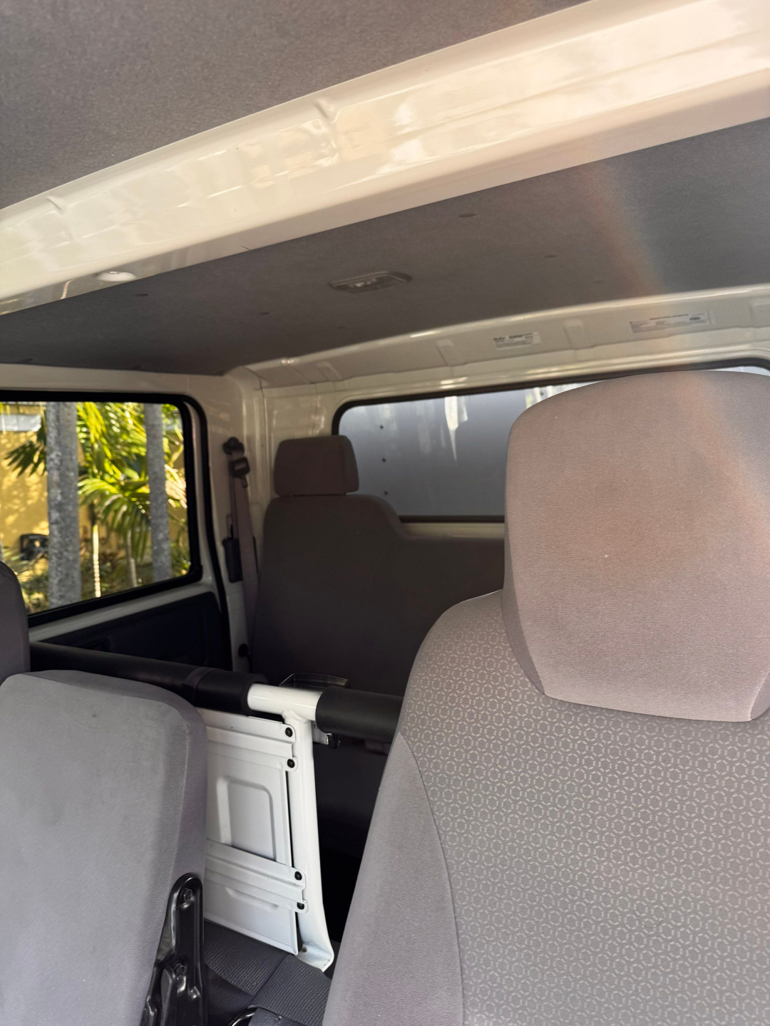 Isuzu NQR interior showing rear seating and cargo area with gray fabric seats and a white partition/backrest