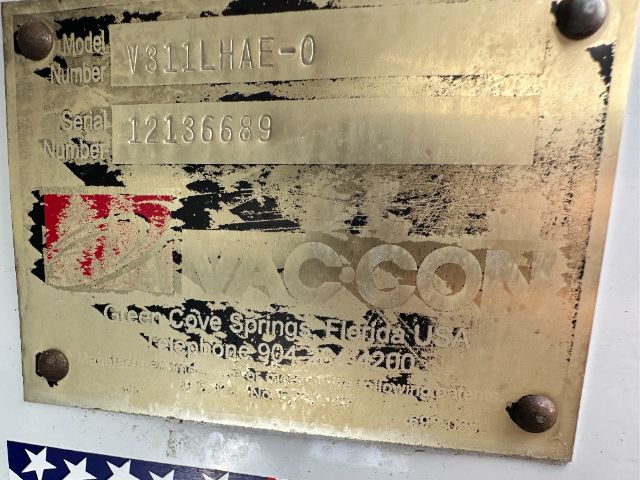 Metal nameplate on Freightliner 114SD showing Model Number V9311HAE-0, Serial Number 121366689, with faded logo and small red sticker nearby.