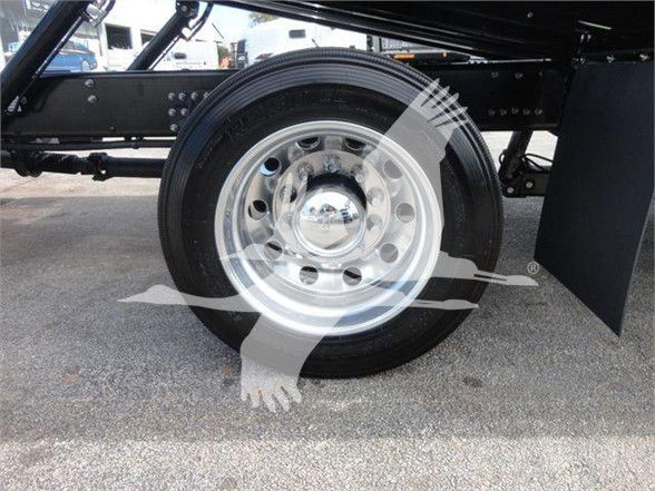 Wheel and suspension area of a new 2025 Mack MD6 tow truck showing polished aluminum wheel with hubcap and ground clearance pieces.