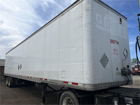 Wabash dry van trailer in white with '887114' number on rear; rigid frame, diamond warning placards, loading door, tandem wheels, side reflectors.
