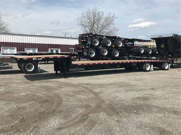 Flatbed trailer with multiple tandem axles carrying stacked wheel sets and a Fontaine logo visible on the side.