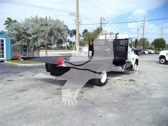 Hino 258LP hooklift truck with flatbed/loader in a parking lot showing rear hydraulic hooklift and metal cab guard.