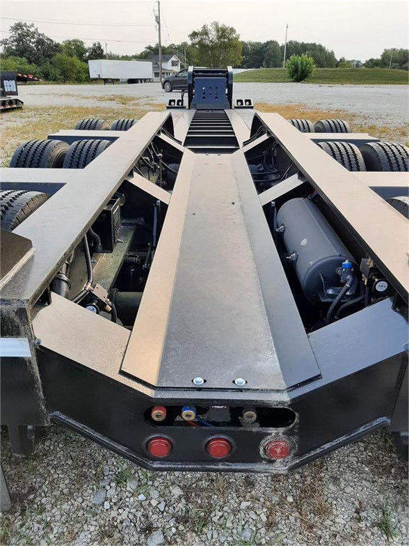 Fontaine 55 ton lowboy trailer rear view showing dual tandem wheels and hydraulic pump/controls, with a central deck beam and toolbox area.