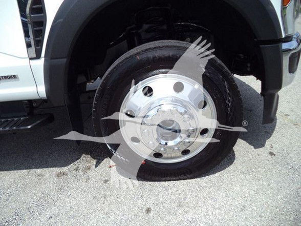 Front wheel and fender of a 2024 Ford F-450 chassis with chrome hubcap and tire, partial view of front bumper and wheel well.