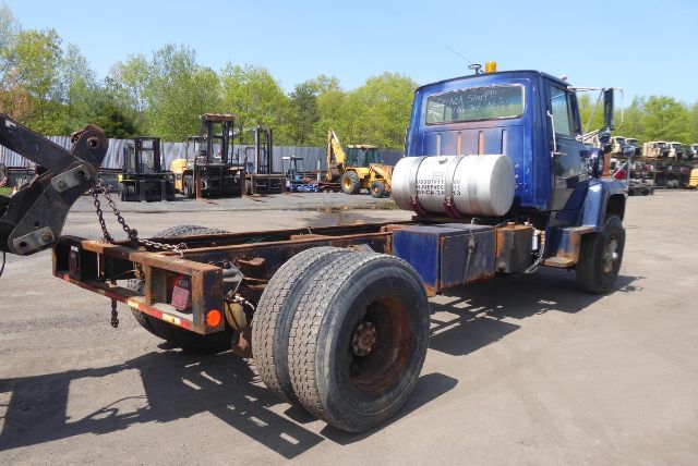Ford 8000 cab and chassis truck with blue cab and exposed frame; two rear axles, propane tank on frame, outdoor lot