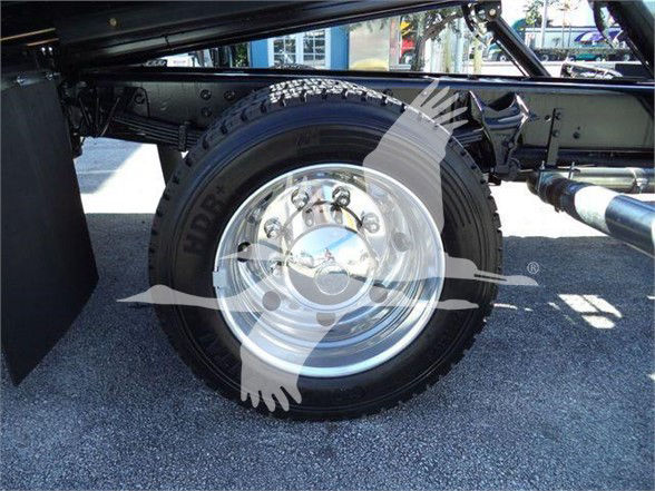 Rear wheel and chassis of a 2023 Chevrolet Silverado 6500HD tow truck showing wheel, tire, and part of suspension with metallic rim.