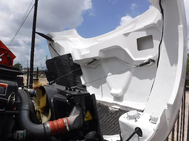 Engine bay view of a white 2018 International 4300 flatbed truck showing engine components and radiator area.