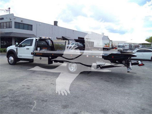 Ford F-550 tow truck with flatbed and towing equipment in a dealership lot.