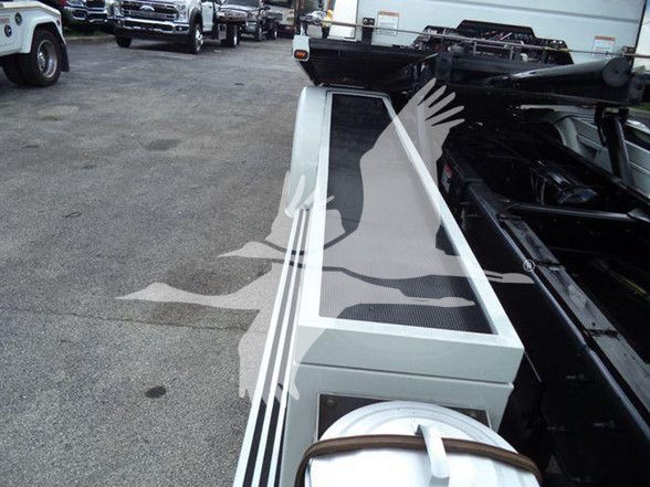 Truck chassis frame showing side rail with white body paint, rear area of tow truck configuration; no legible model text visible in this crop.