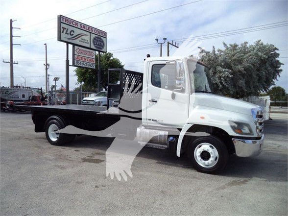 2017 Hino 258LP hooklift truck, white cab, flatbed with black deck. VIN plate not visible. Stock number T52712. Background shows dealership signage.